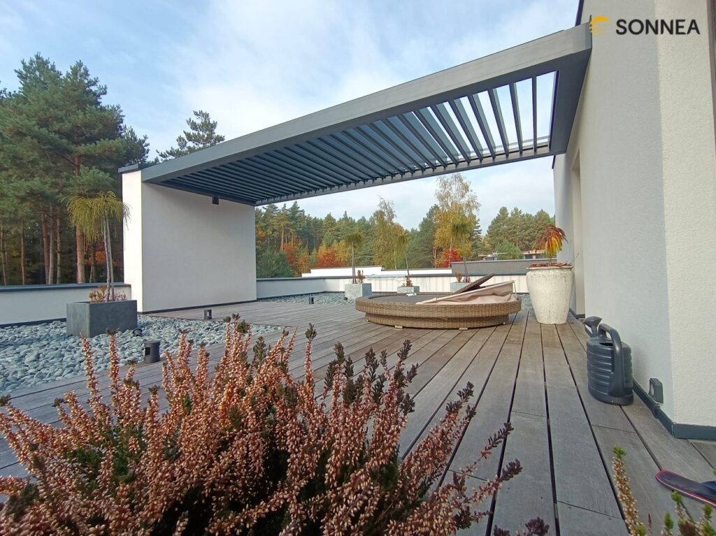 Anthrazitfarbene Lamellenpergola, montiert zwischen Wand und Fassade