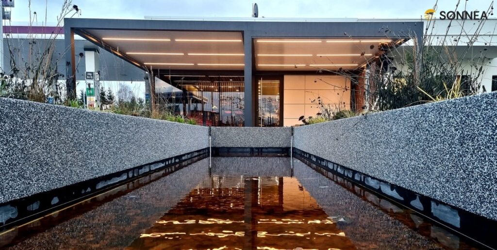 Lamellenpergola mit Beleuchtung und Jalousien an einer Tankstelle